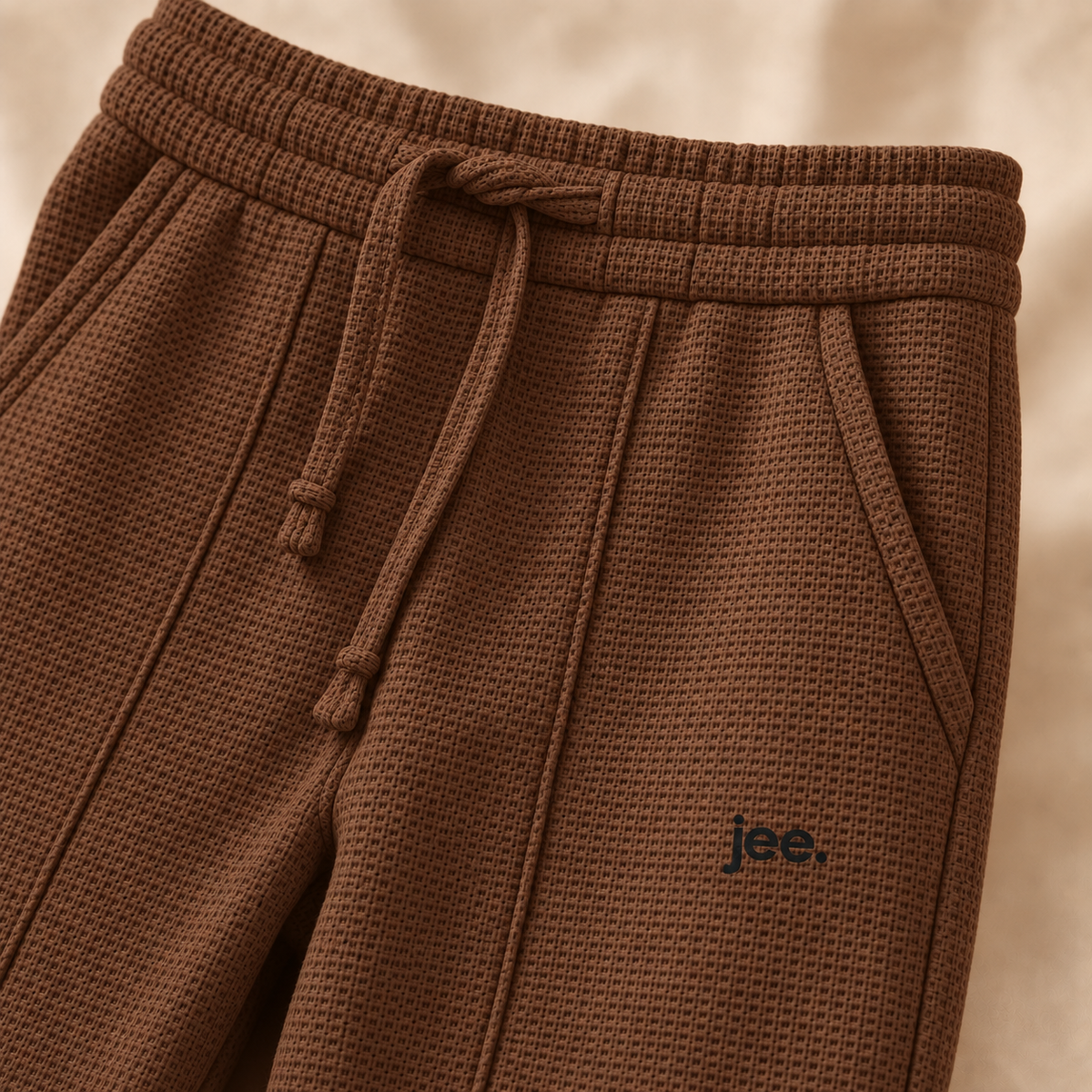 Premium fine-knit Brown trouser close-up with jee. logo